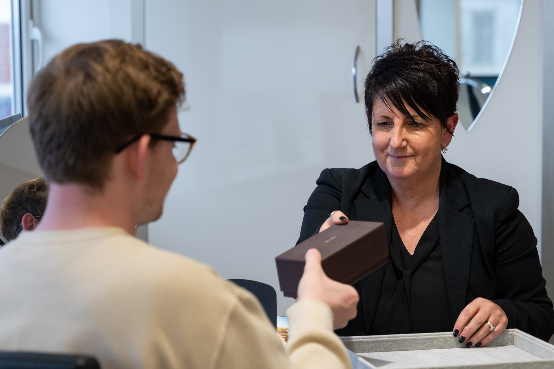 Professional exchanging package at service counter with smiling representative