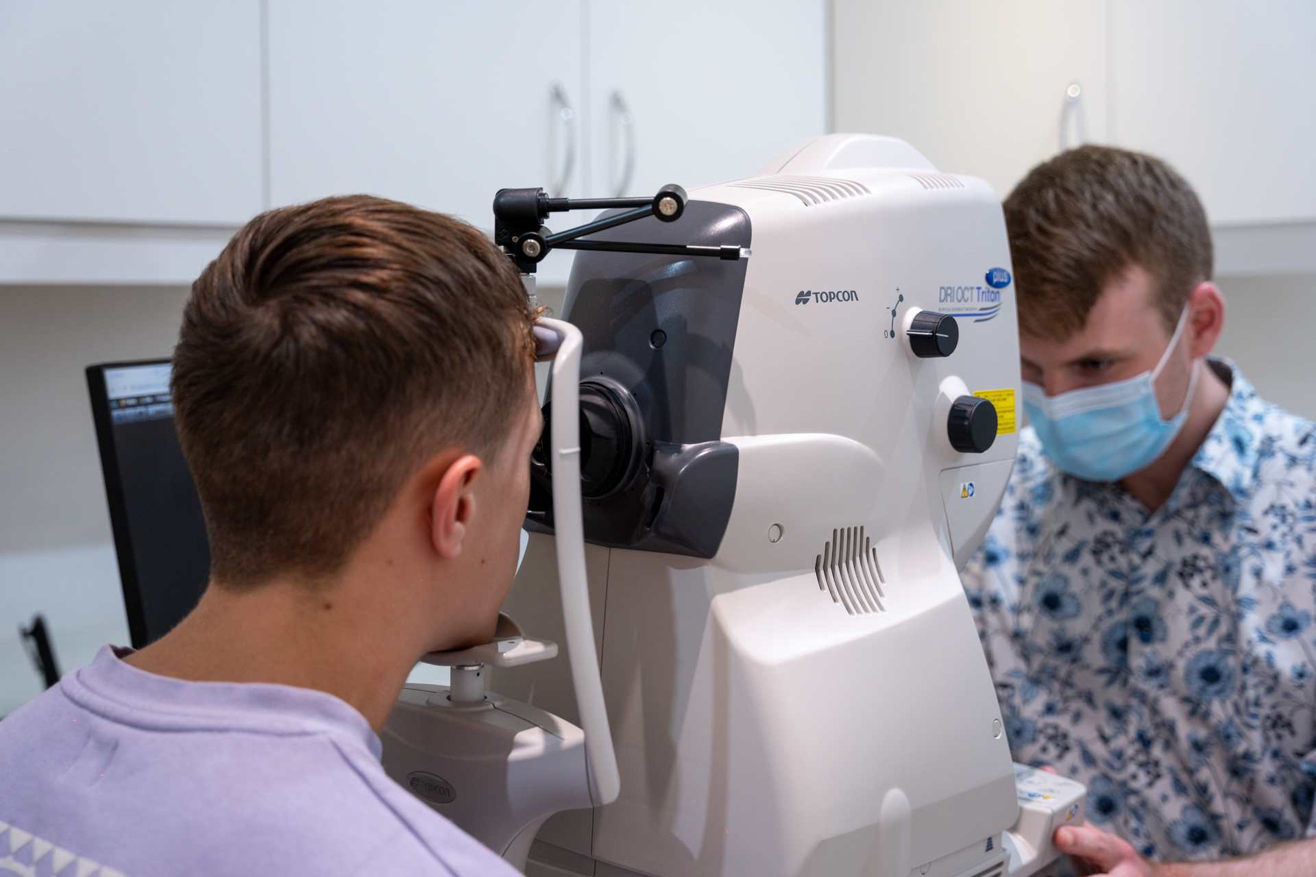 Patient getting eye exam with Topcon medical device and healthcare professional