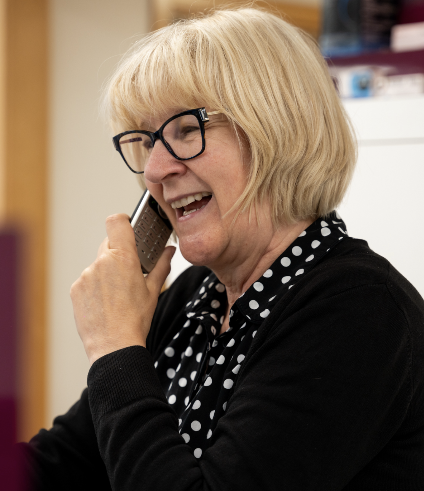 Laughing older woman with glasses talking on mobile phone