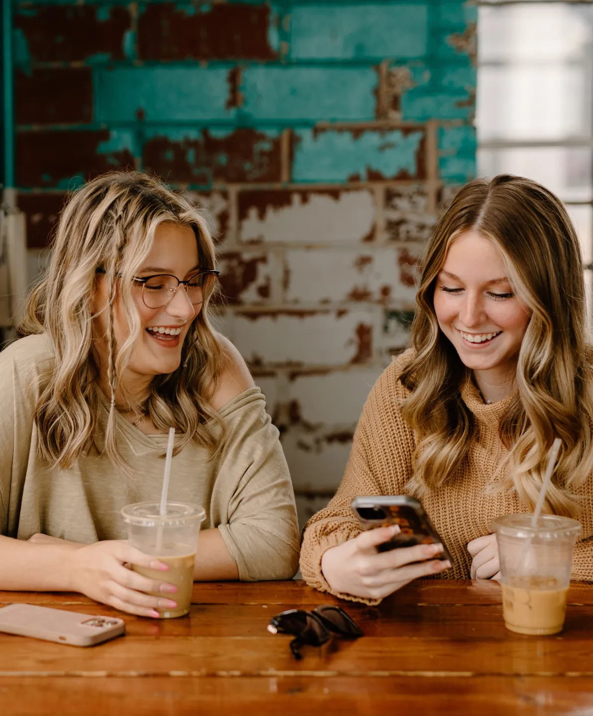 Two friends laughing and enjoying coffee together at a wooden table
