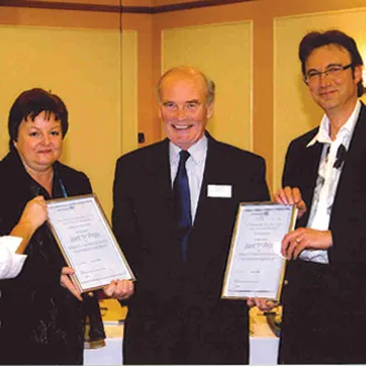 Three professionals posing with certificates at an awards ceremony