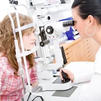 Eye doctor performing eye exam on young patient using slit lamp