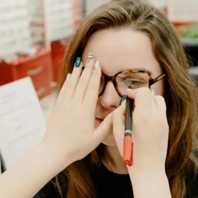 Person covering one eye while getting makeup applied