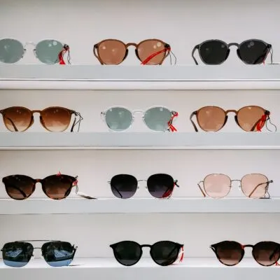 Display of various stylish sunglasses arranged neatly on white shelves