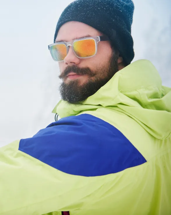 Bearded man in winter gear with reflective sunglasses and green jacket
