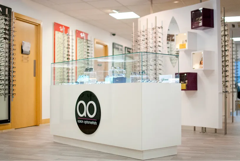 Optical shop interior with glass display case and eyeglass frames on walls