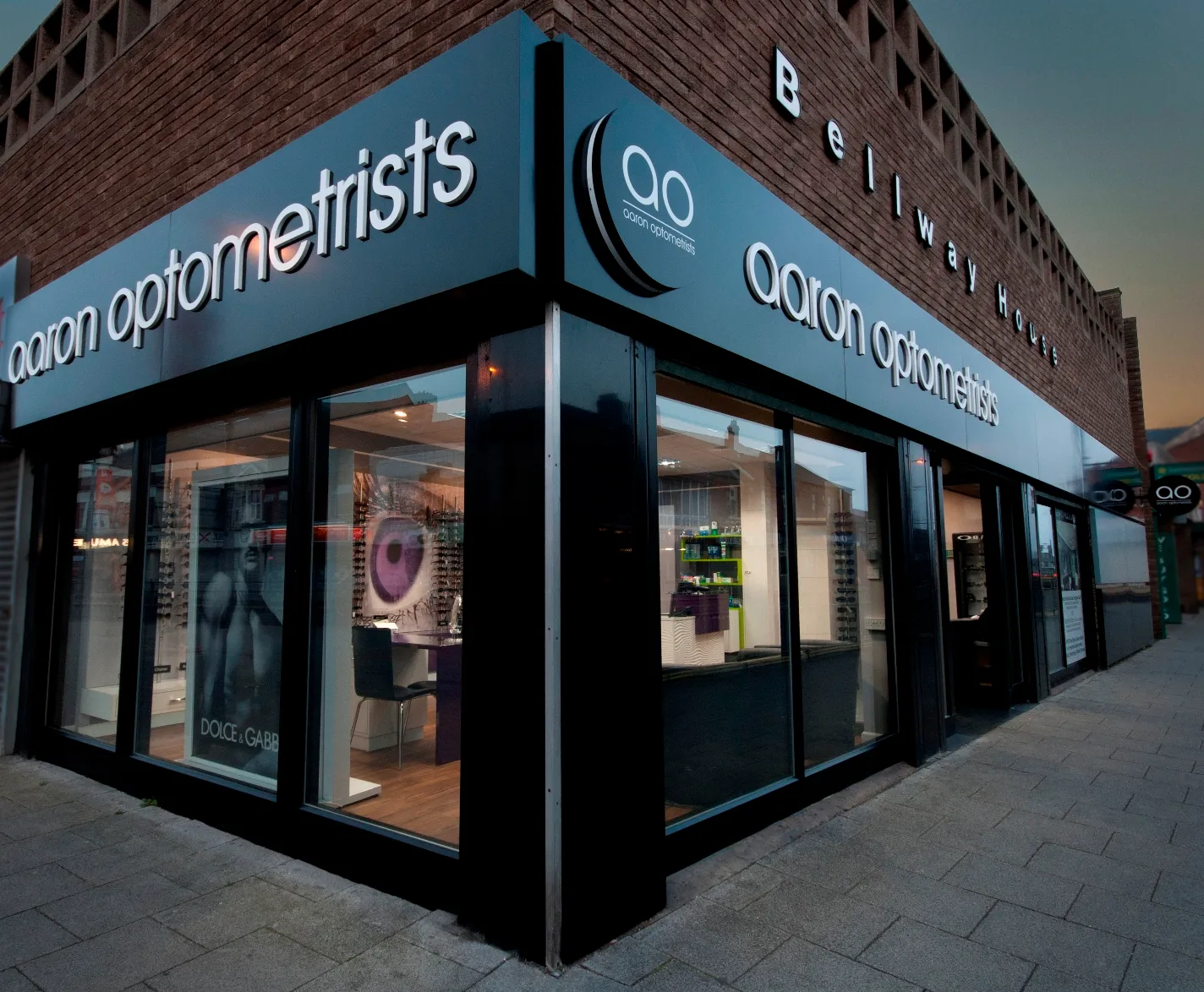 Aaron Optometrists storefront with glasses display at twilight