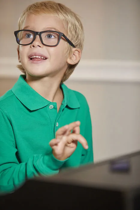 Smiling child in green polo and glasses looking up