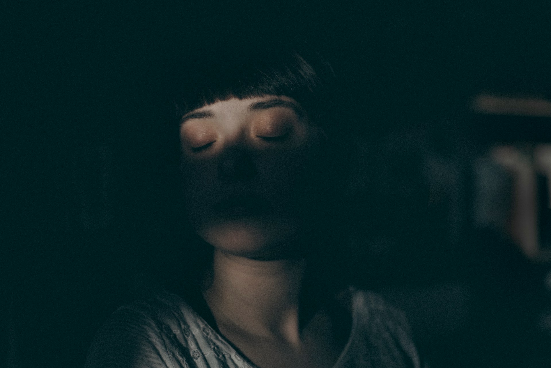 Blurred portrait of a person with closed eyes in dark setting