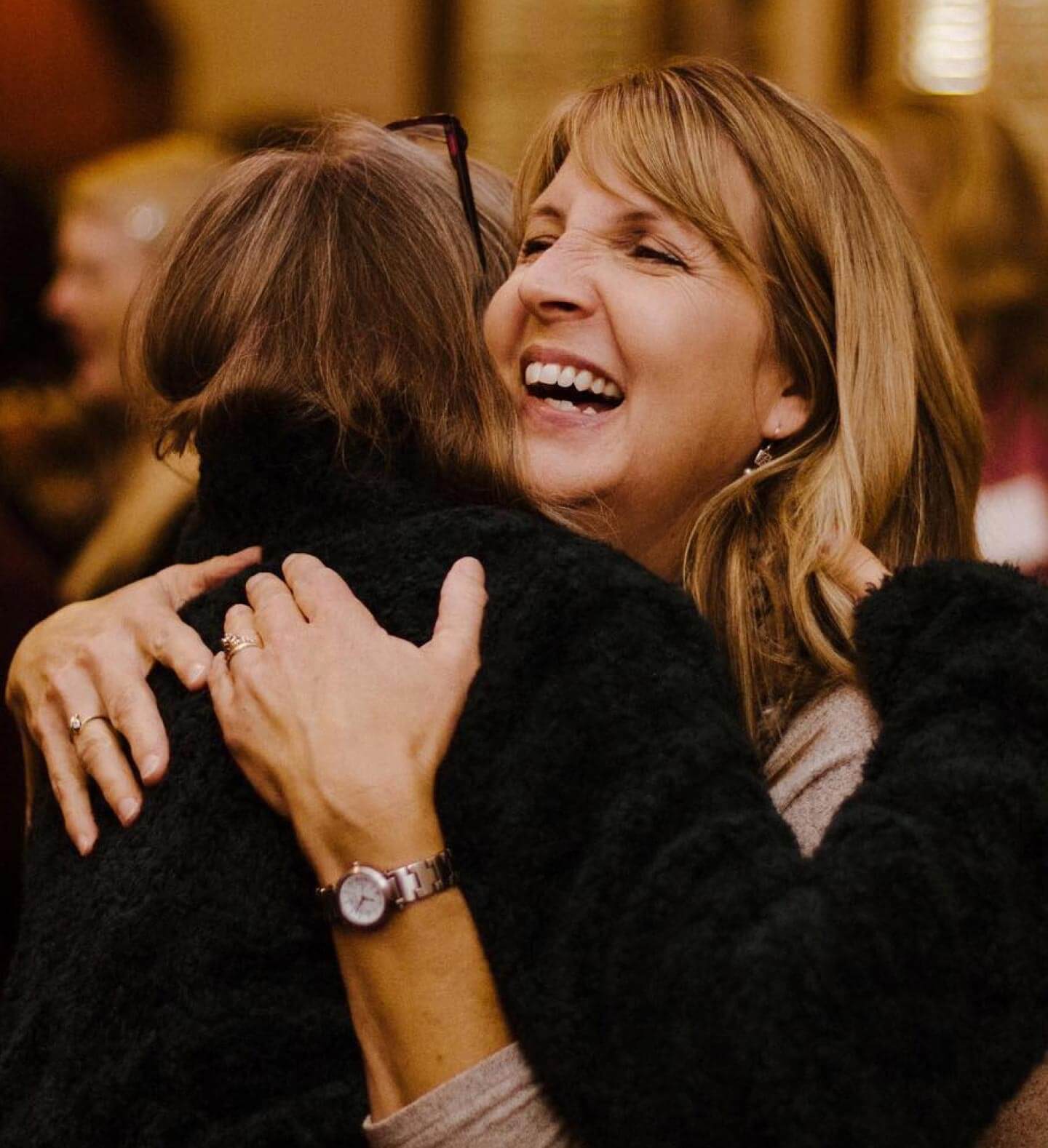 Two women embracing in a friendly hug at a Harvest Church event