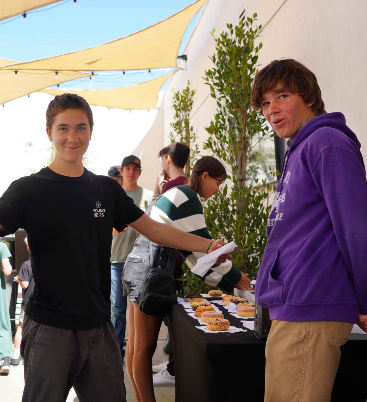 A photo of two Harvest Church’s Young Heirs youth group volunteers having fun while serving doughnuts during a Family Sunday service at church