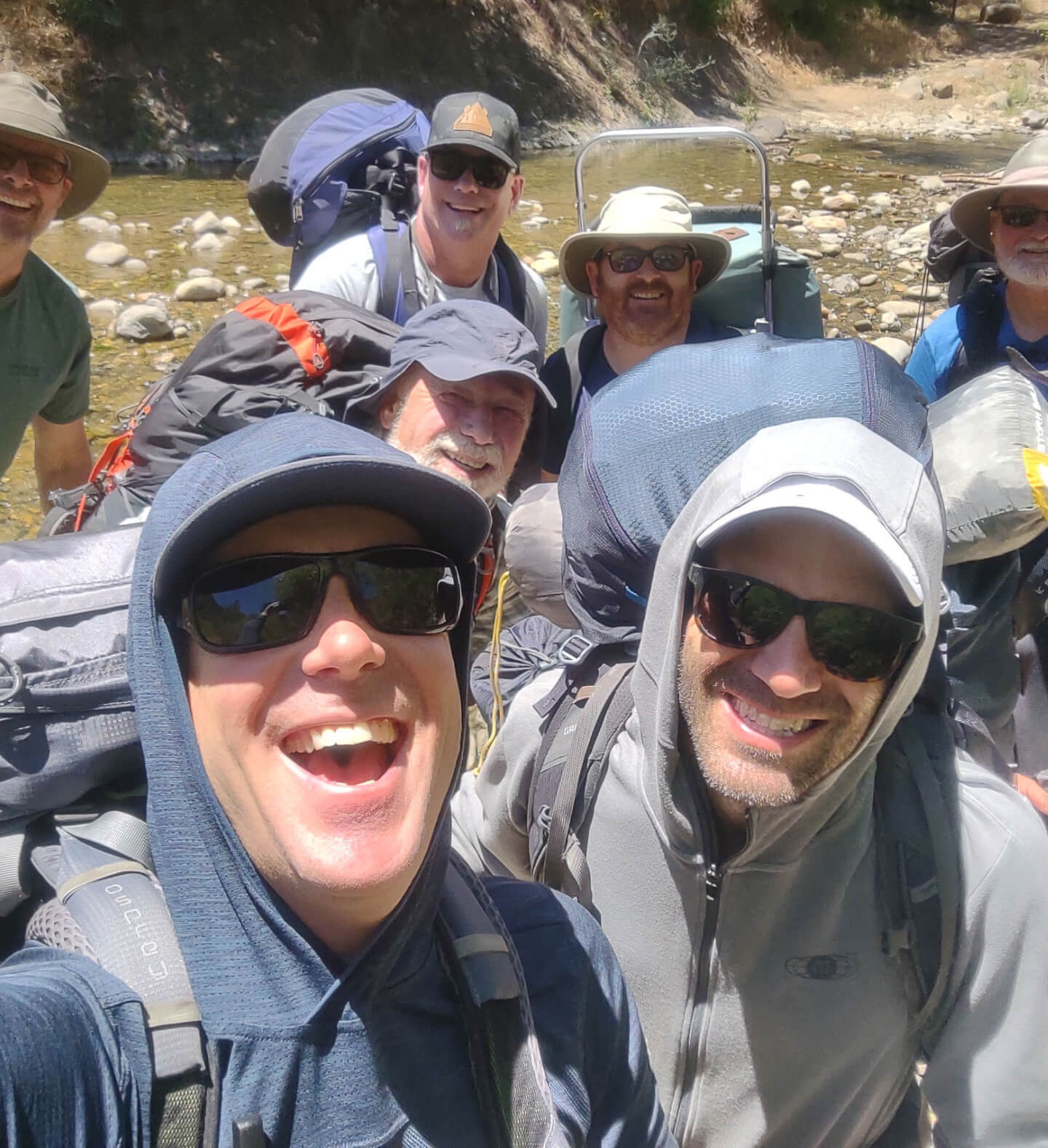 An active and playful photo of the Harvest Church men’s group beside a river and mountainside during an adventurous backpacking trip