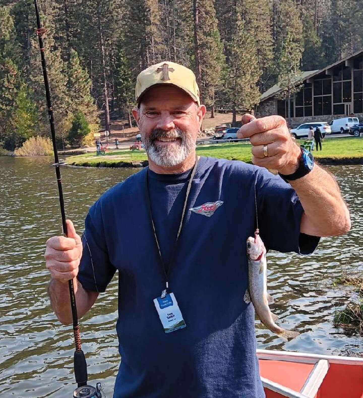 Harvest Church elder, Gary Tucker, smiling with fishing pole in right hand, and massive, record-setting rainbow trout in his left hand.