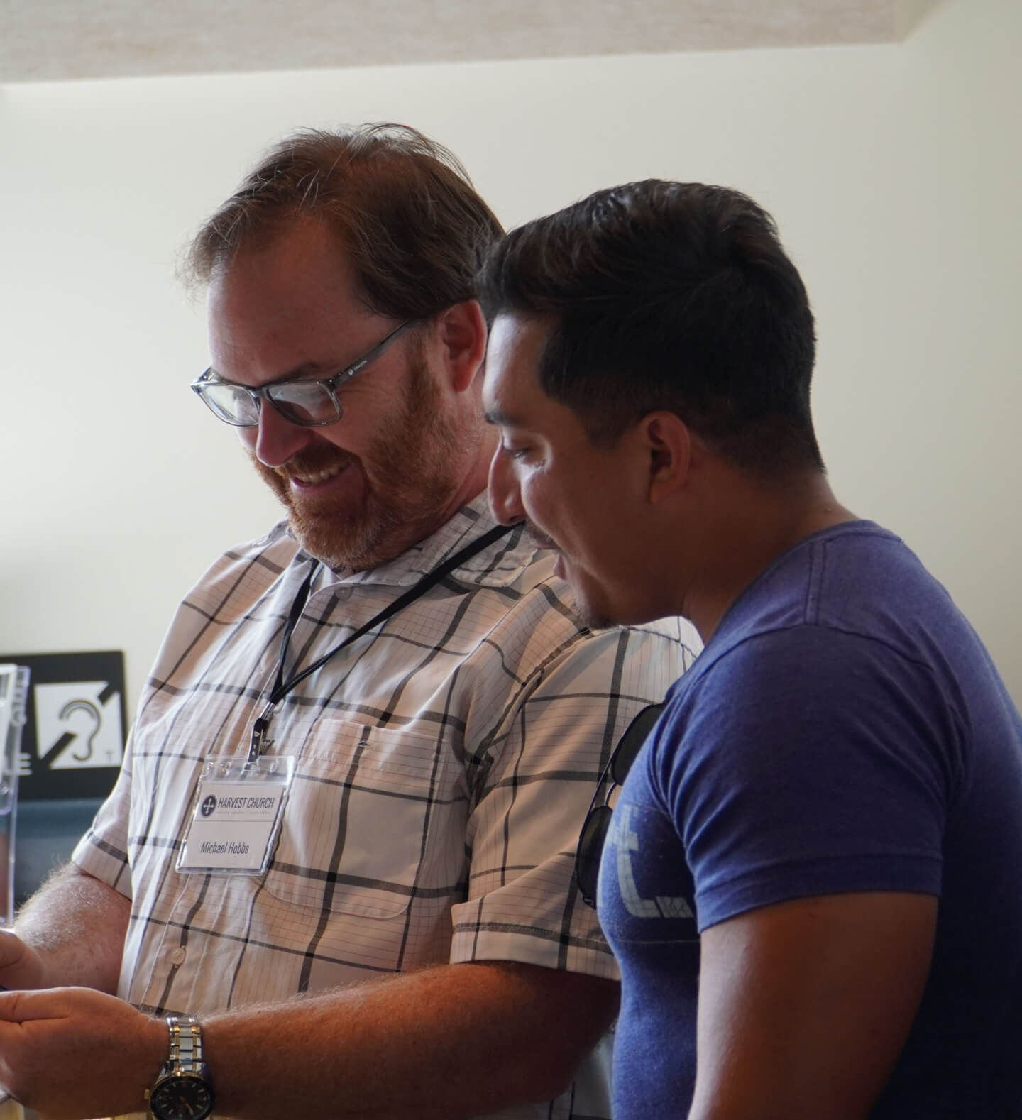 Two men from Harvest Church volunteering at the info desk, smiling during a brief moment while serving