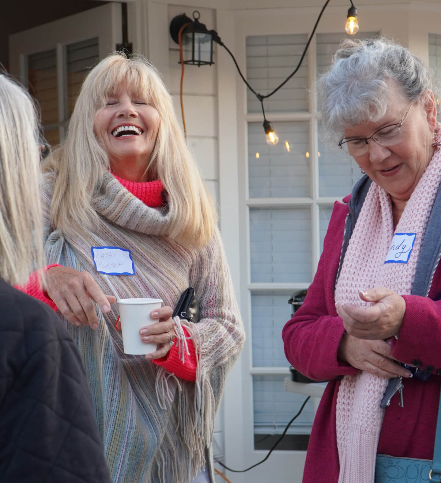 A closeup of three women sharing smiles and laughter at an outdoor dinner and fellowship event on the patio of the Christian Harvest Church in the Village of Arroyo Grande