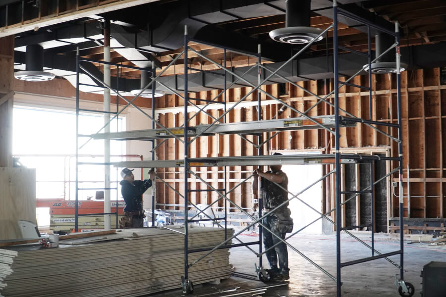 Another big step! A picture of two men setting up scaffolding while doing construction inside of the new Harvest Church Worship Center
