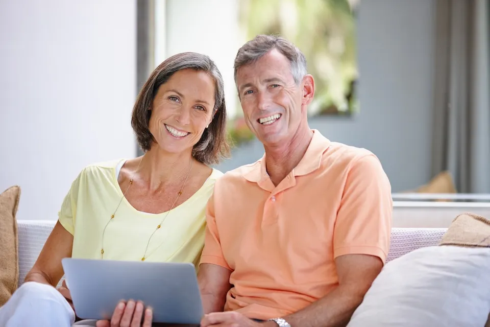 Couple on couch with laptop smiling