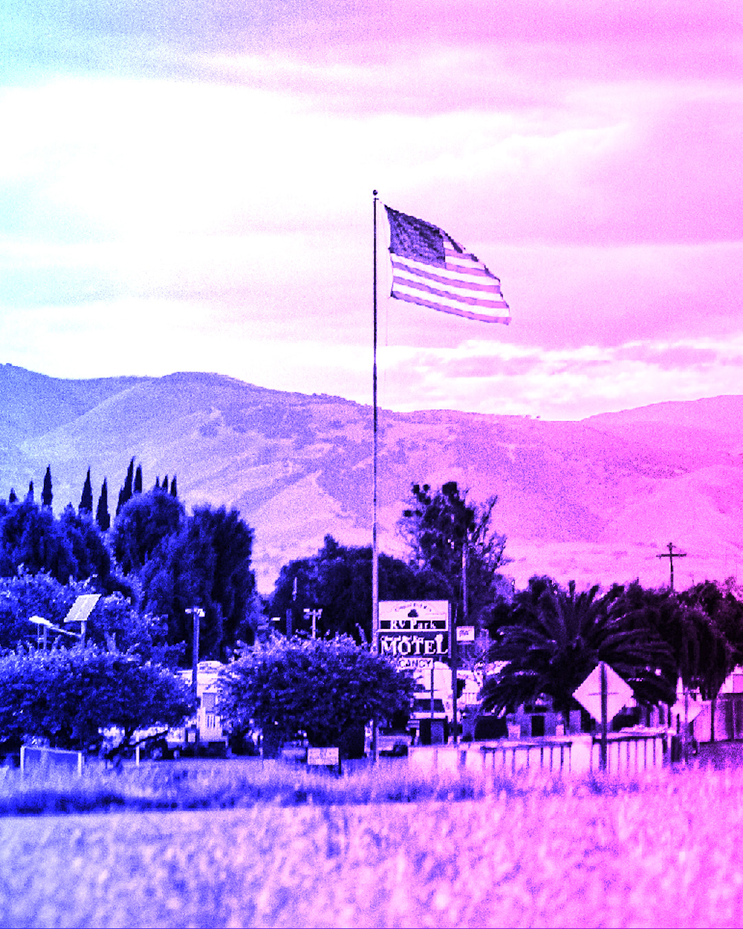 American flag flying over a small mountain town in America with a purple overlay