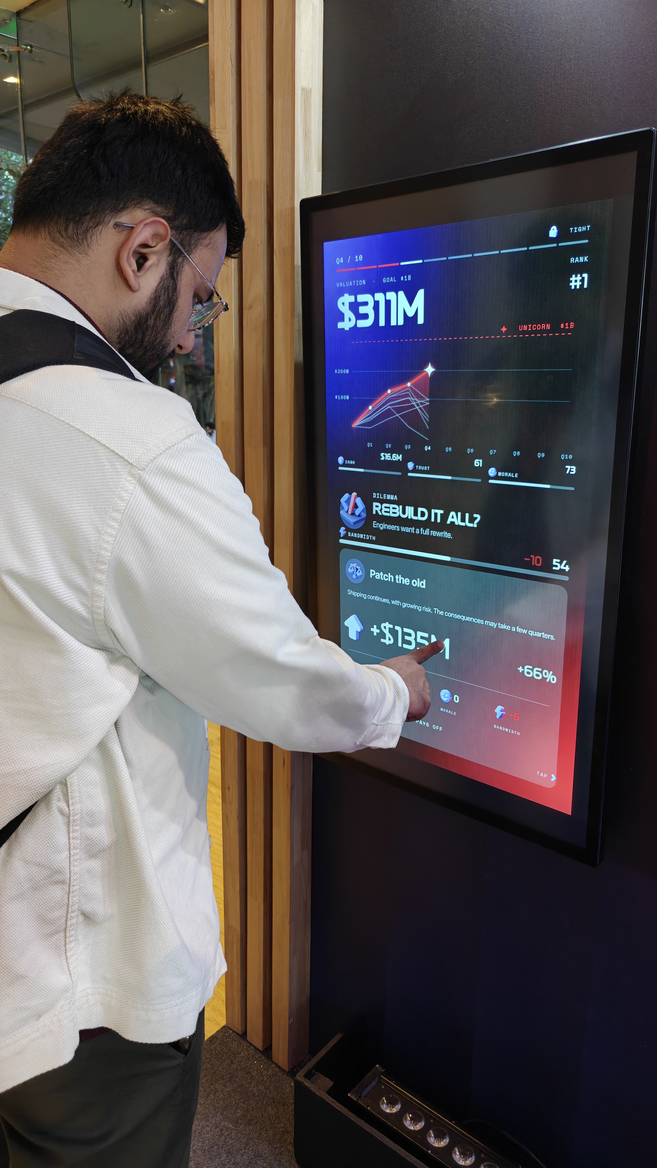 Nishant from Flowtrix playing Order of One on a touchscreen, choosing an answer to the Rebuild it all? dilemma