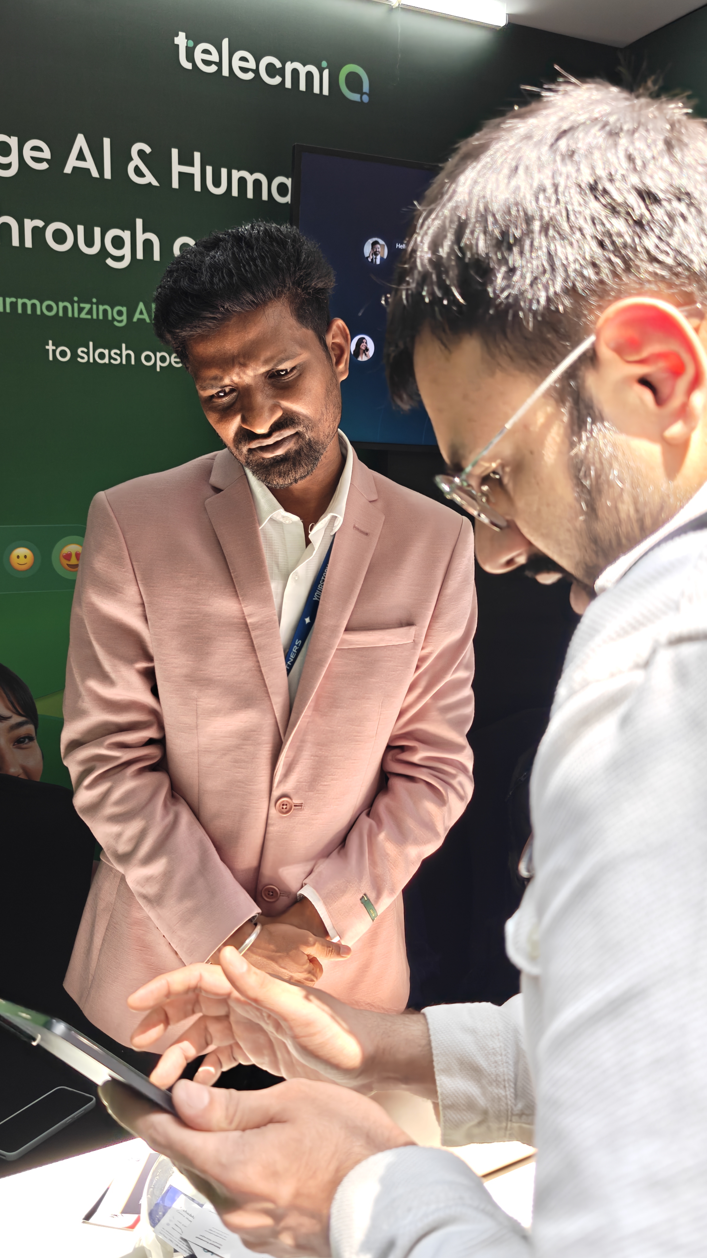 A TeleCMI team member showing Nishant from Flowtrix a product demo on a phone at TechSparks 2026