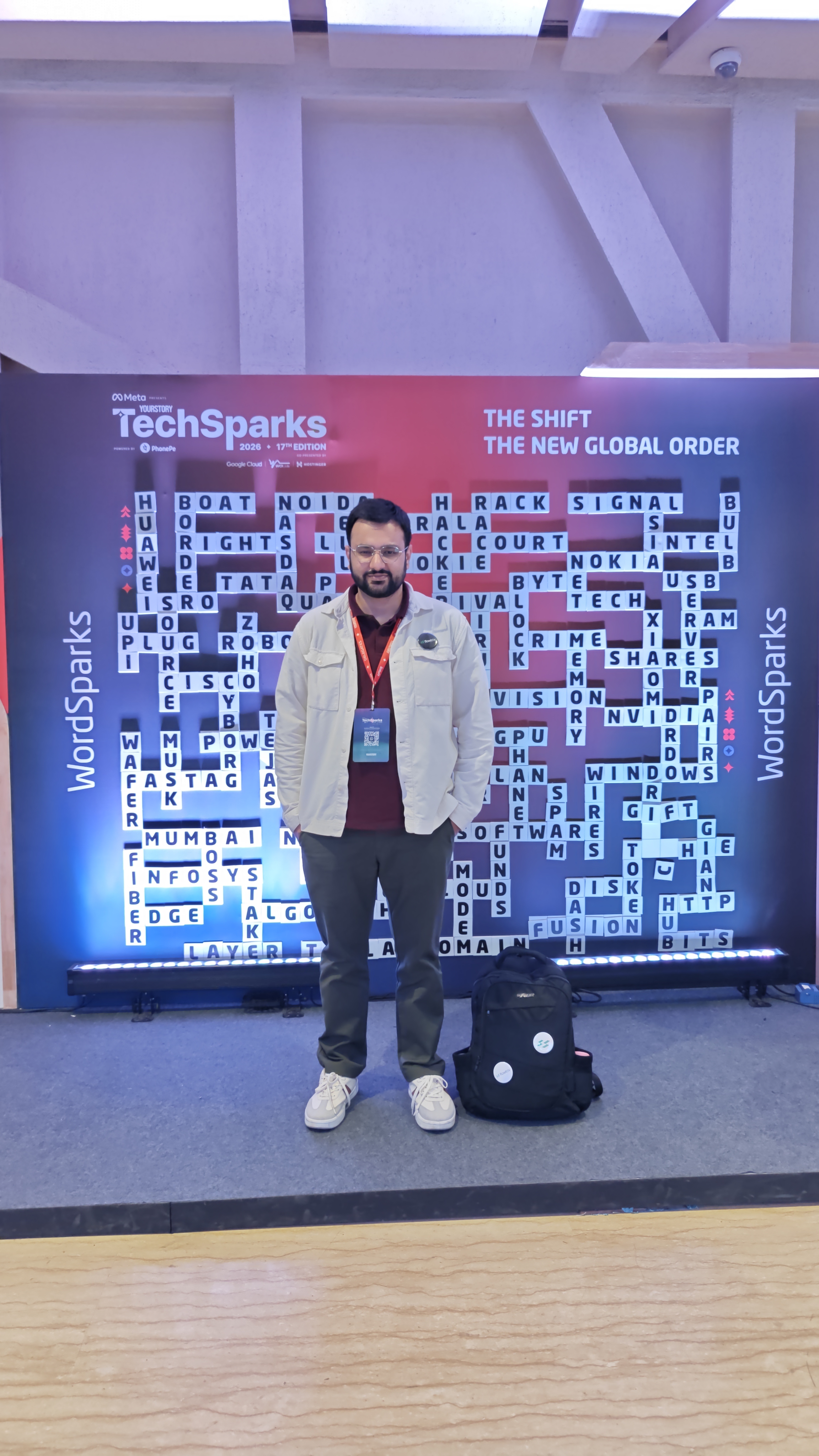 Nishant from Flowtrix standing in front of the WordSparks tech crossword wall at TechSparks 2026