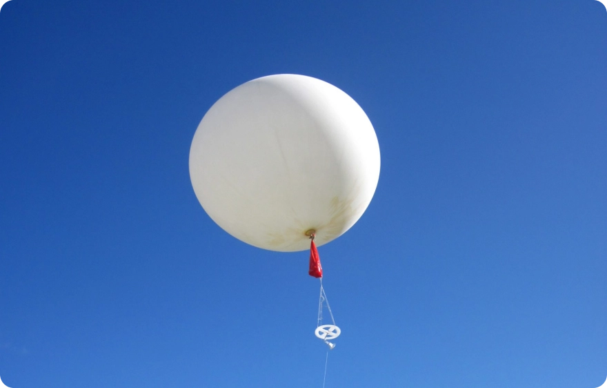 White balloon with red string, floating in the sky