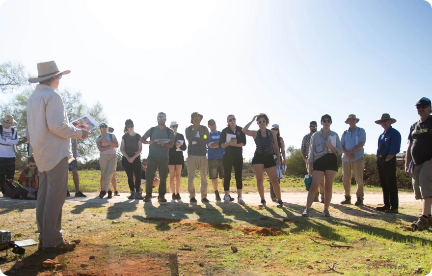 A diverse group of people standing around a man in a hat