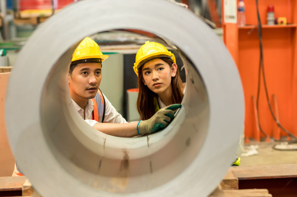 Two engineers inspecting a large metal cylinder, illustrating hands-on collaboration and attention to detail, key aspects of lean management practices in the manufacturing industry.