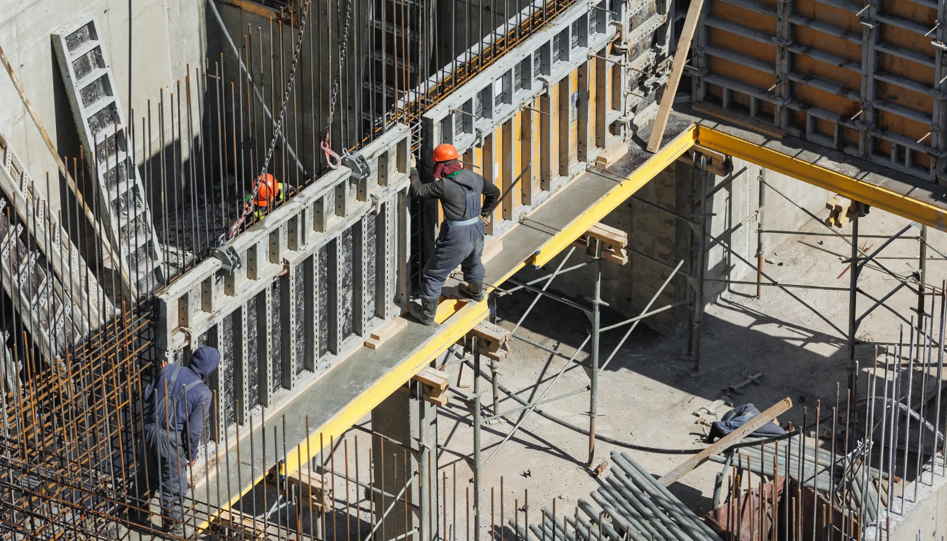 Bauarbeiter bei Schalungsarbeiten auf einer aktiven Baustelle als Sinnbild für Risikomanagement im Bauwesen.