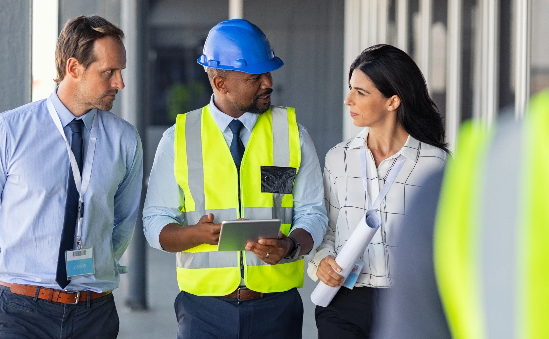 Bauleiter und Projektverantwortliche besprechen Projektdaten auf einem Tablet auf einer Baustelle.