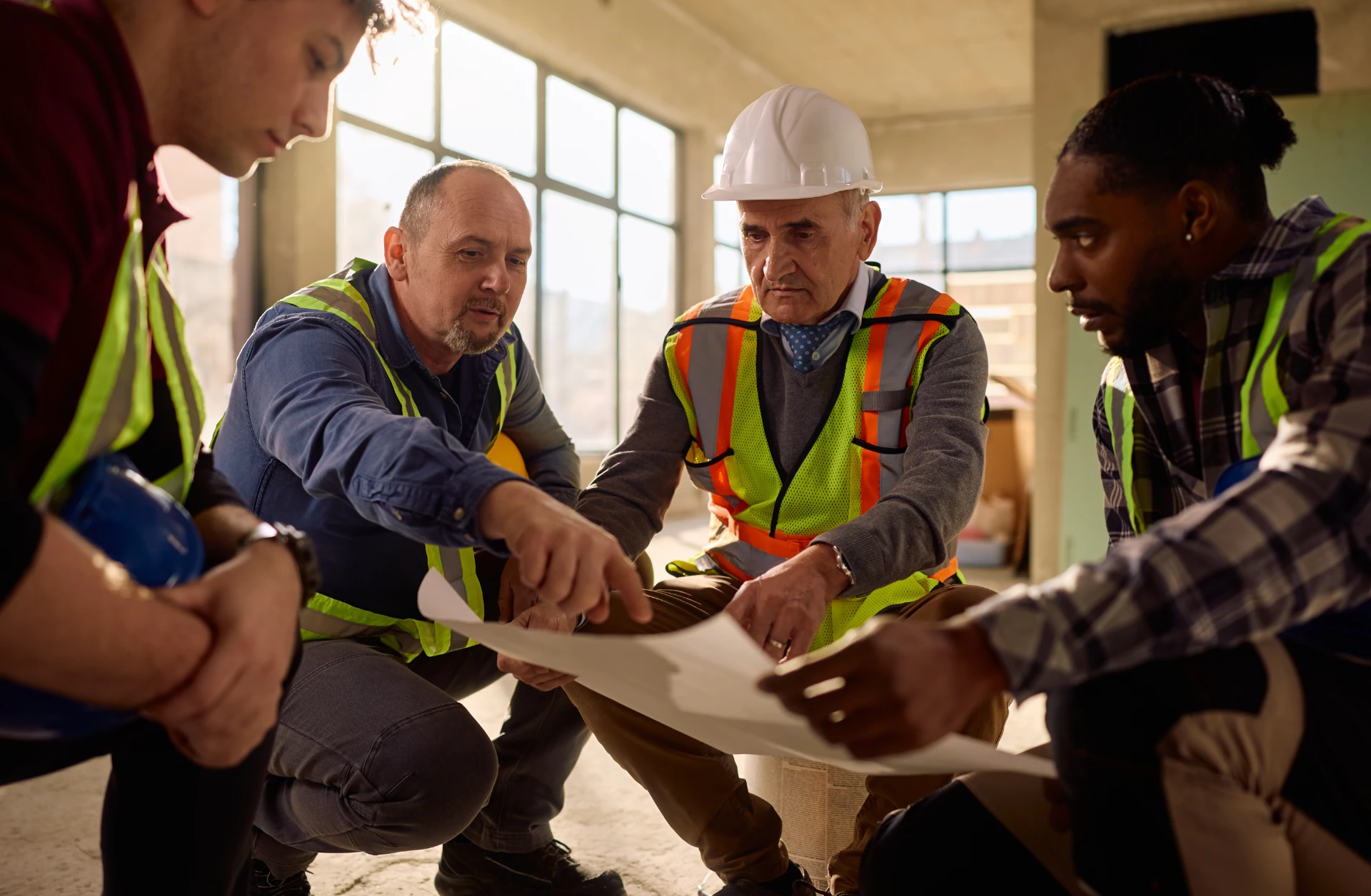Construction team reviewing plans on site, coordinating workflow changes across trades during active project work.