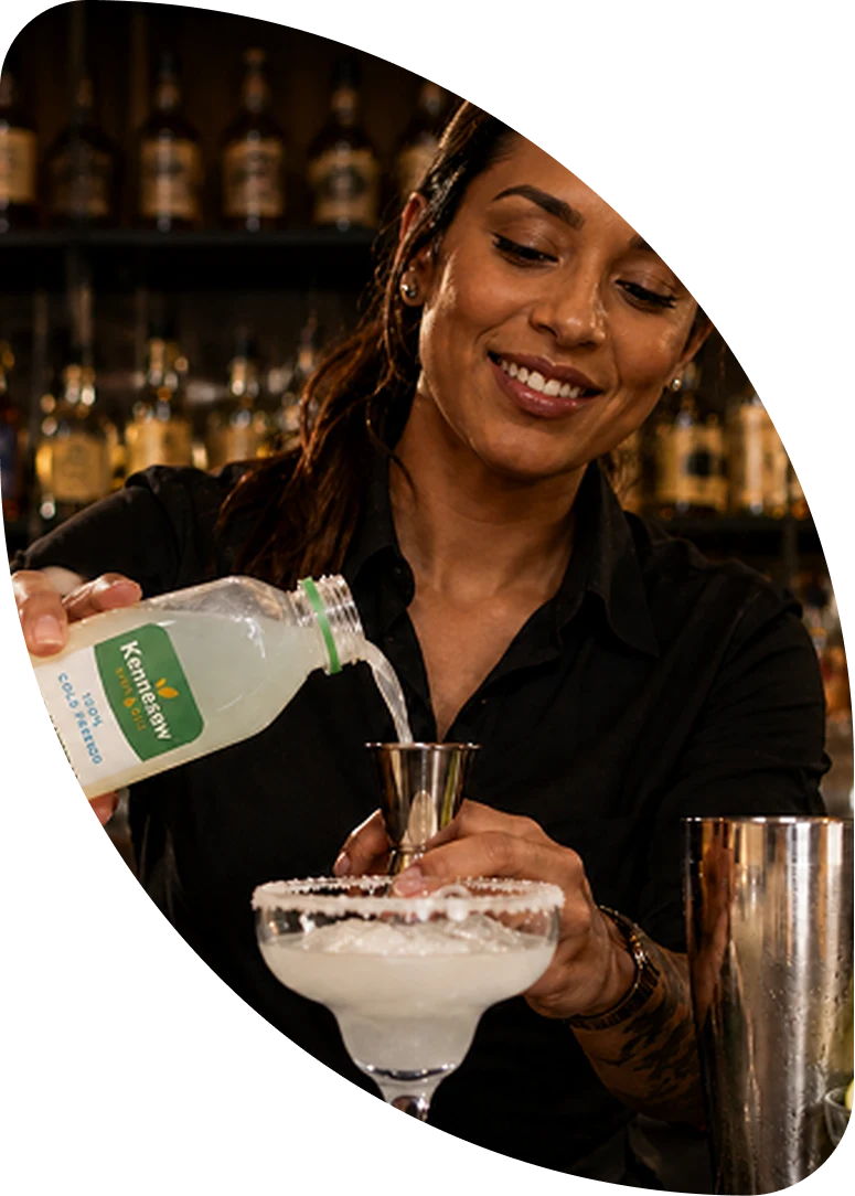 A bartender pouring Kennesaw Lemonade into a jigger over a salt-rimmed margarita glass