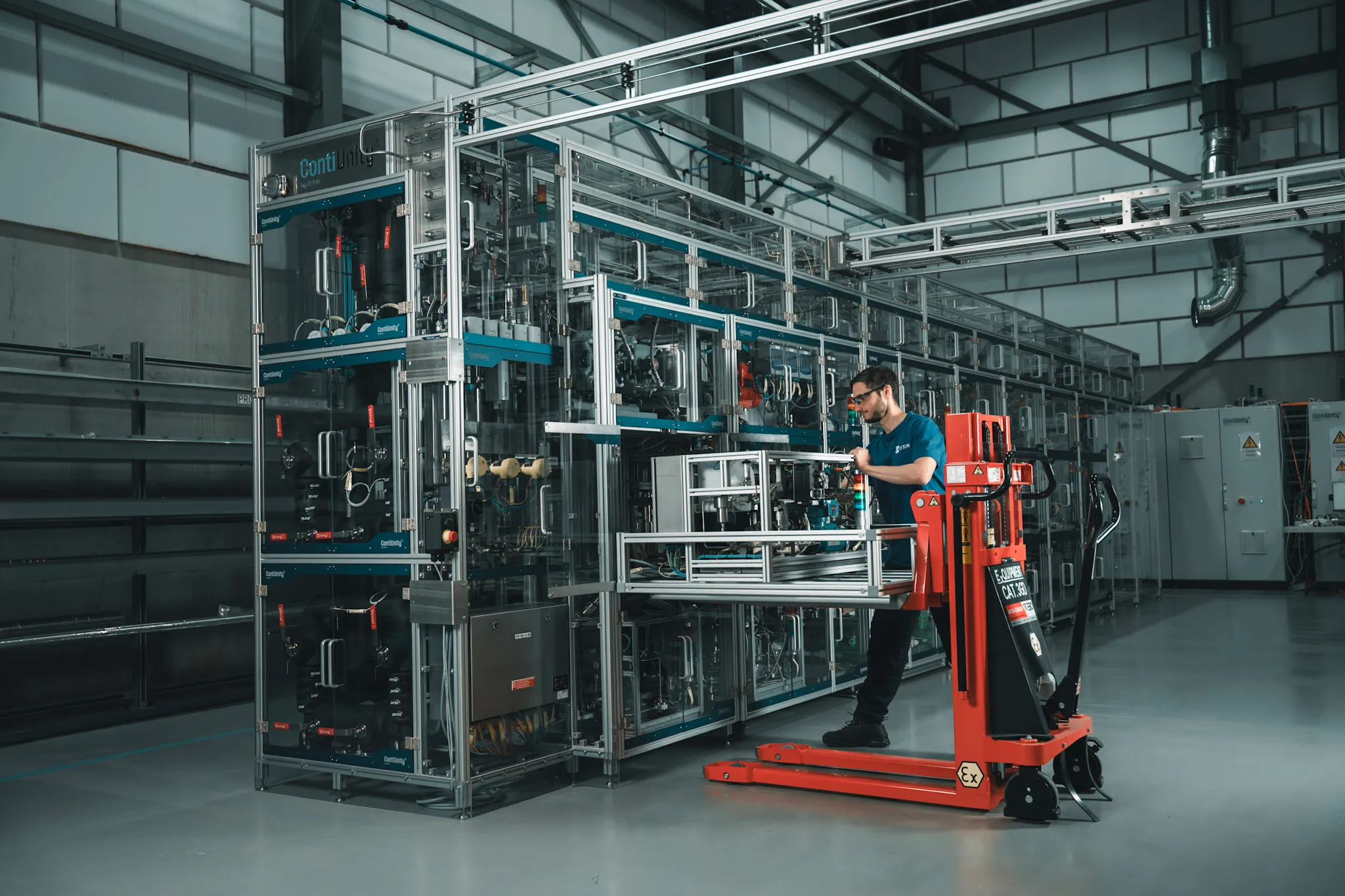 Technician operating a red pallet jack to change a module on the ContiUnity system.