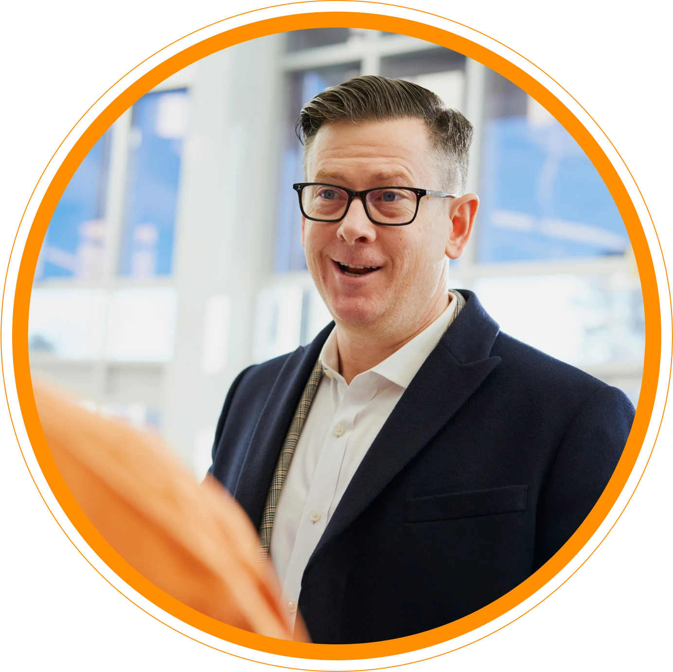 An image of a happy, helpful man. The photos is bordered in an orange circle, with a thinner circle outlining that.