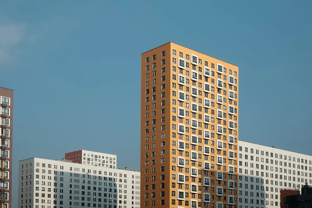 Buildings on a clear blue day with a yellow apartment building at the centre.
