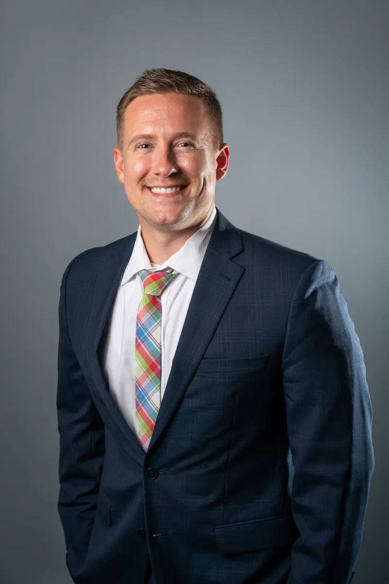 A blonde man in a suit posing for a professional portrait photograph.