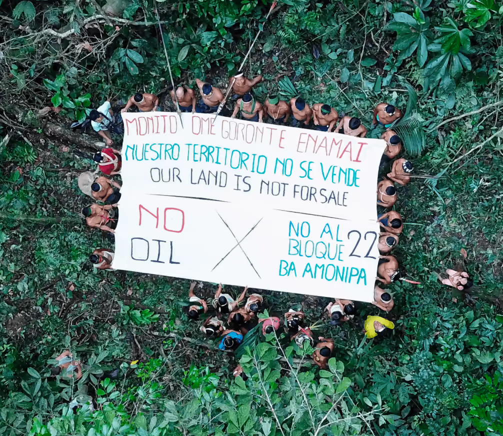 Indigenous people holding up a white banner reading: "Our land is not for sale"
