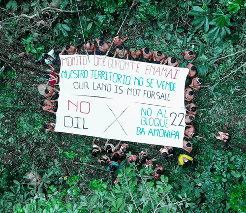 Indigenous people holding up a white banner reading: "Our land is not for sale"