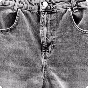 Close-up of the front of blue denim jeans showing button, zipper, and pockets.