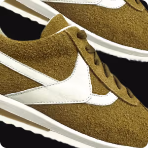 Close-up of a brown suede sneaker with white swoosh logo and white sole.