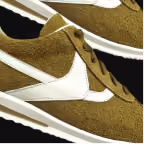 Close-up of a brown suede sneaker with white swoosh logo and white sole.