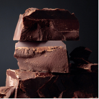 Close-up of stacked large chunks of dark chocolate against a dark background.