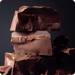 Close-up of stacked large chunks of dark chocolate against a dark background.