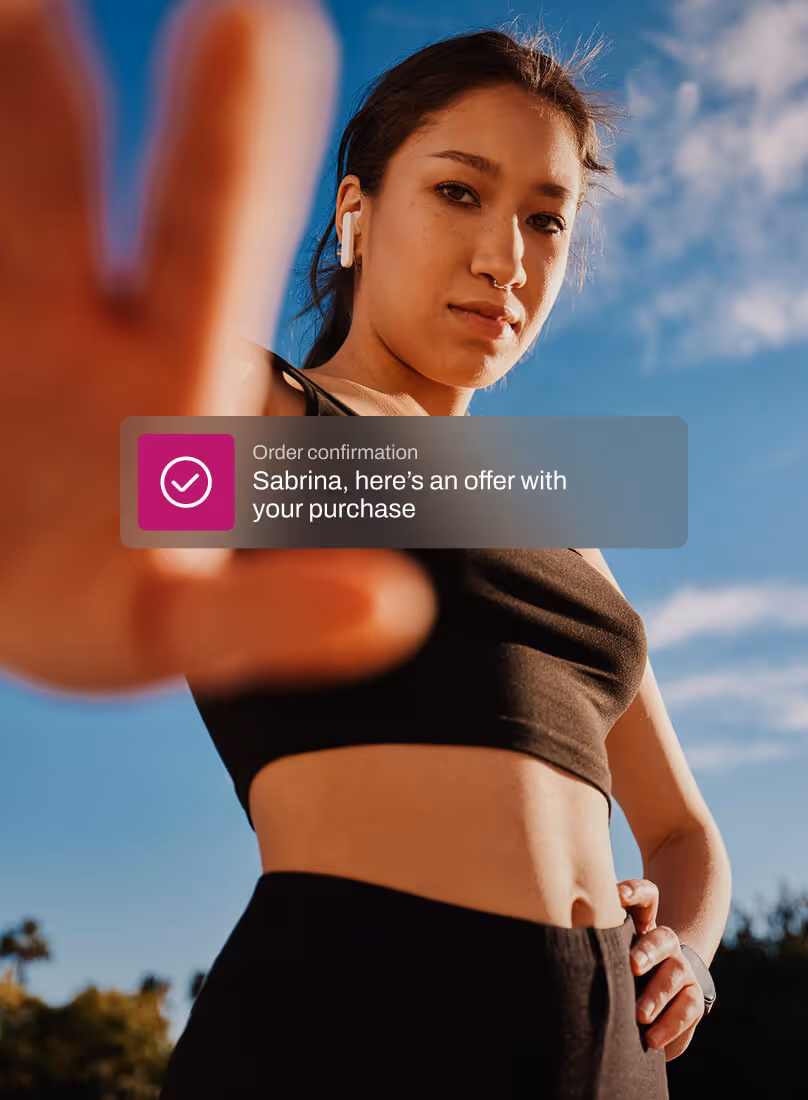 Young woman in black sportswear reaching hand toward the camera outdoors under blue sky with a notification overlay about order confirmation and purchase offer.