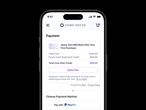 スマートフォンの画面には、「Home Decor」という名前の電子商取引サイトの支払いページが表示されます。一番上には、「Jenny、最初の購入で $50 が戻ってきます」と書かれたプロモーション用のクレジットカードオファーがあります。表示されているカードの画像は、白い背景にMastercardとVisaのロゴが入っています。以下の価格内訳は、合計金額が100.00ドルで、将来のカード明細書クレジットが-50.00ドルで、クレジット後の合計金額は50.00ドルです。価格概要の下に「Apply Now」というラベルの付いた紫色のボタンがあります。ボタンの下にあるメモには、対象となる購入から 8 ~ 12 週間後に明細書クレジットが付与されることが明記されています。プロモーションセクションの下部に、目立たない「Powered by Rokt — プライバシーポリシー」というメッセージが表示されます。その下で、ユーザーは支払い方法を選択できます。PayPalでの支払いオプションが強調表示されており、わかりやすいPayPalのロゴとブランドが表示されています。