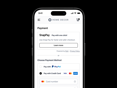 「Home Decor」のモバイルチェックアウトの支払いページを表示するスマートフォン画面。一番上のセクションでは、ワンクリック決済オプションと「詳細」ボタンで「SnapPay」を宣伝しています。以下では、ユーザーはPayPalとクレジットカードのどちらで支払うかを選択できます。クレジットカードオプションが選択され、カードロゴ (Visa、Mastercard、Amex) が表示されます。カード番号を入力するフィールドが一部表示されます。