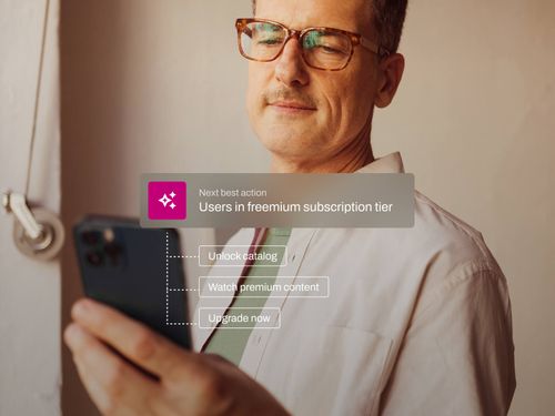 Man with glasses holding a smartphone with an overlay displaying options to unlock catalog, watch premium content, and upgrade now for freemium subscription users.