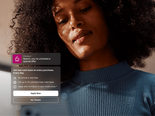 A woman with natural curly hair wearing a ribbed blue turtleneck looks down at a screen, softly lit by warm sunlight. A pop-up notification on the image reads, “Naomi, you’ve unlocked a special offer,” promoting a cash-back credit card with benefits like no fees and up to 3% Daily Cash. Two buttons below read “Apply Now” and “No Thanks.”