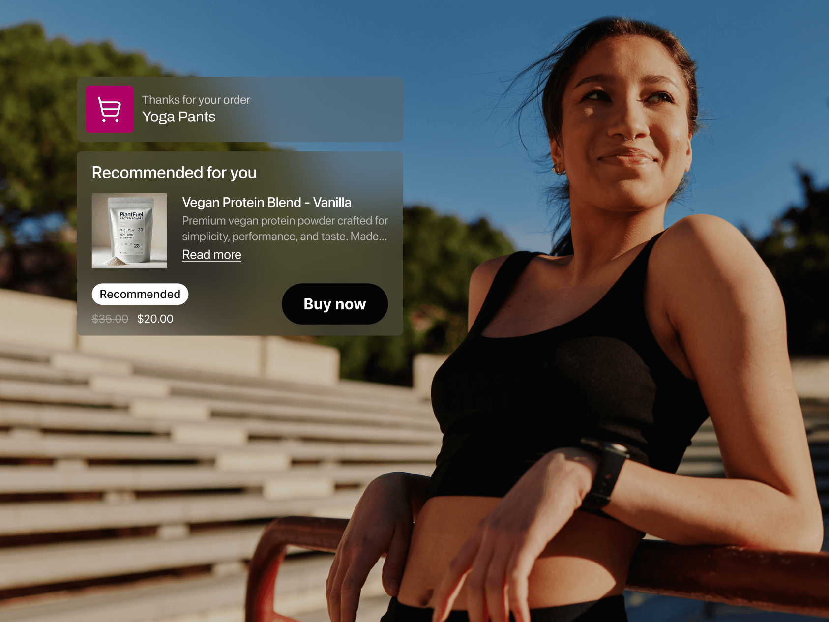 A young woman in athletic wear smiles confidently while leaning against a red railing at an outdoor stadium under bright sunlight. She wears a black sports bra and fitness tracker, with her hair pulled back and wisps blowing in the breeze. On the left side of the image, overlaid digital shopping notifications appear. The first confirms an order for "Yoga Pants," and the second recommends a product titled "Vegan Protein Blend – Vanilla" with an image of a white protein pouch, price drop from $35.00 to $20.00, and a prominent "Buy now" button. The background features empty bleachers and leafy trees under a clear blue sky, blending fitness lifestyle with e-commerce personalization.