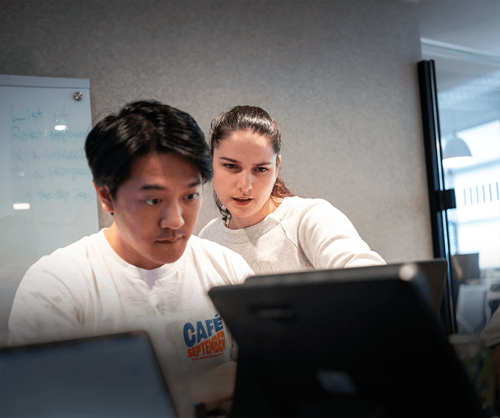 Two people working together focused on laptop screens in an office setting.